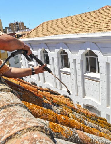 Worker cleaning a roof with high pressure water